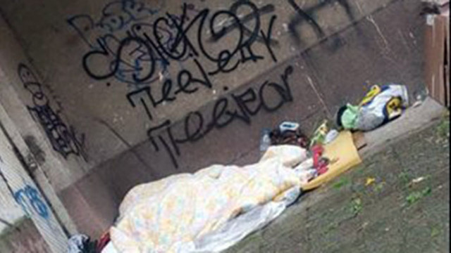 Двама възрастни бездомници мъж и жена спят под тераса на